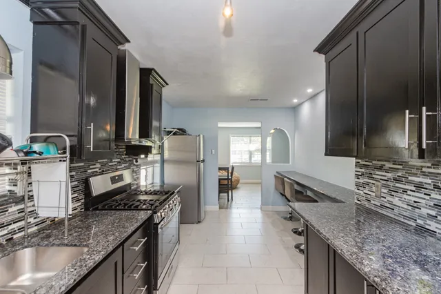 a kitchen with stainless steel appliances granite countertop a sink stove and cabinets