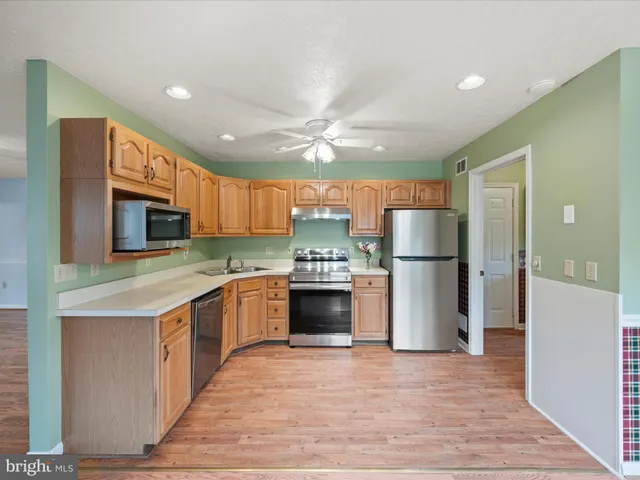 a kitchen with stainless steel appliances granite countertop a refrigerator stove a sink and a oven with wooden floor