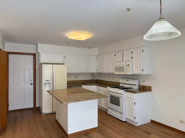 a kitchen with stainless steel appliances granite countertop a stove a refrigerator and a sink with wooden floor