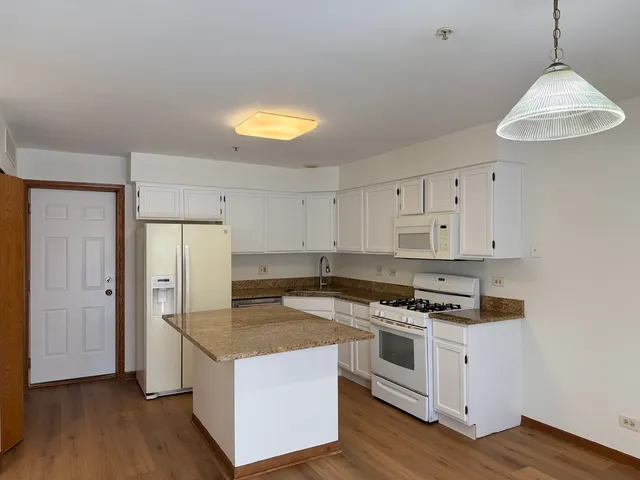 a kitchen with stainless steel appliances granite countertop a stove a refrigerator and a sink with wooden floor