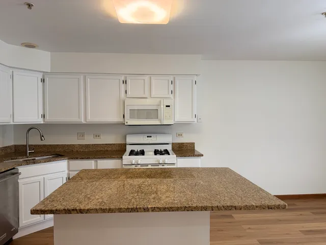 a kitchen with granite countertop a sink a stove and white cabinets