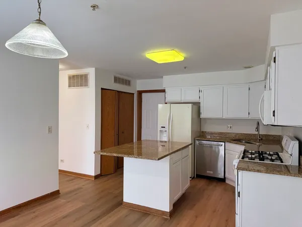 a kitchen with stainless steel appliances granite countertop a refrigerator a stove and a wooden floors