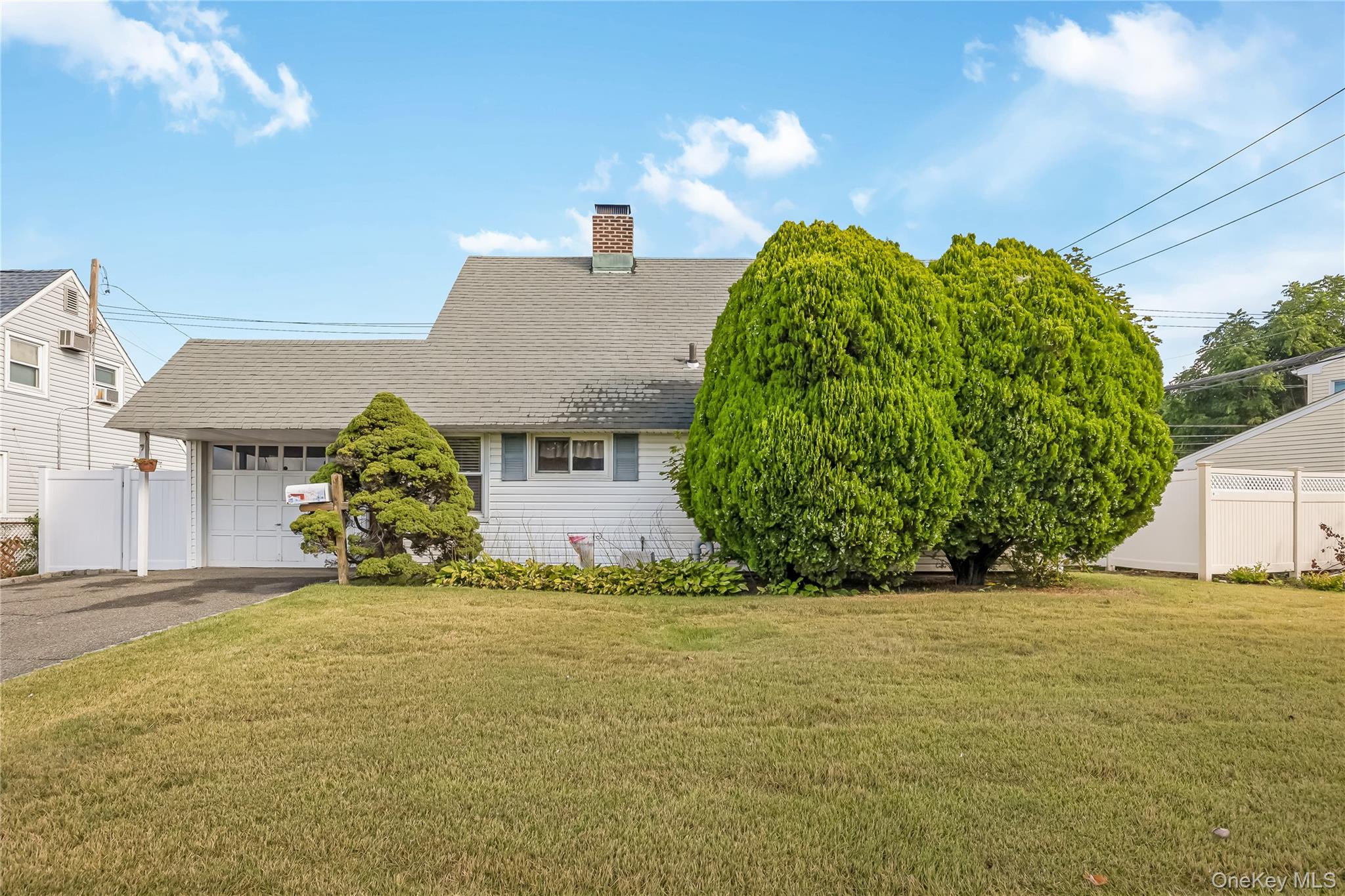 93 Flamingo Road Levittown, NY 11756 - Photo 1 of 1 View of front of home with a garage, a chimney, asphalt driveway, and a shingled roof