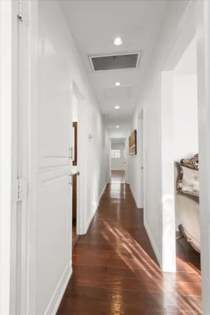 a view of a hallway with wooden floor and a living room