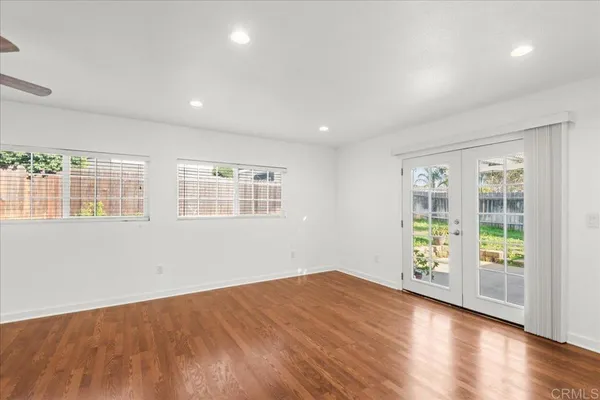 an empty room with wooden floor and windows