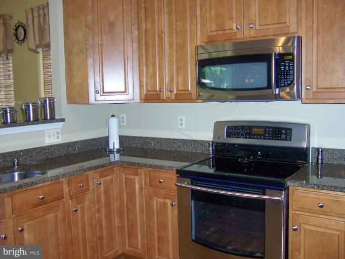 5957 Sandy Ridge Elkridge, MD 21075 - Photo 9 of 30 a kitchen with stainless steel appliances granite countertop a stove a microwave and a sink
