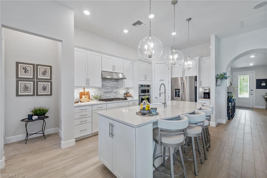 2703 Aviamar Circle Naples, FL 34114 - Photo 11 of 49 a kitchen with a dining table chairs stainless steel appliances and cabinets