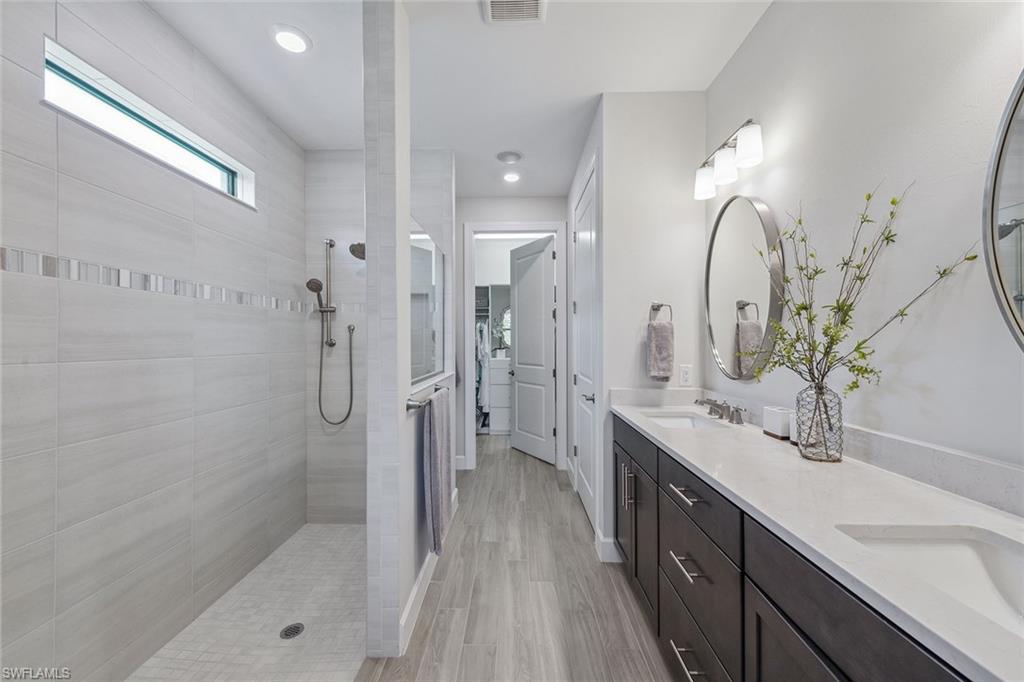 2703 Aviamar Circle Naples, FL 34114 - Photo 18 of 49 a spacious bathroom with a double vanity sink a large mirror a shower and a bathtub