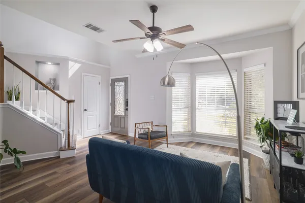 a living room with couches and a dining table with wooden floor