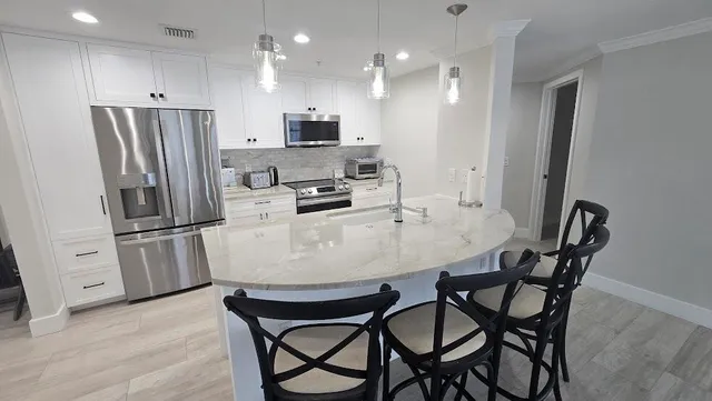 a kitchen with stainless steel appliances a refrigerator a stove a sink a dining table and chairs