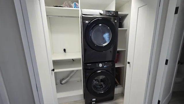 a utility room with dryer washer and a view of bedroom