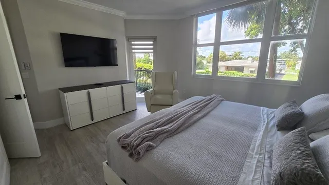 a bedroom with a bed tv and a window