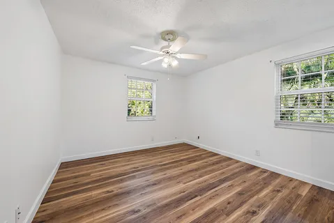 an empty room with windows and fan