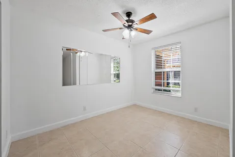 an empty room with a window and ceiling fan