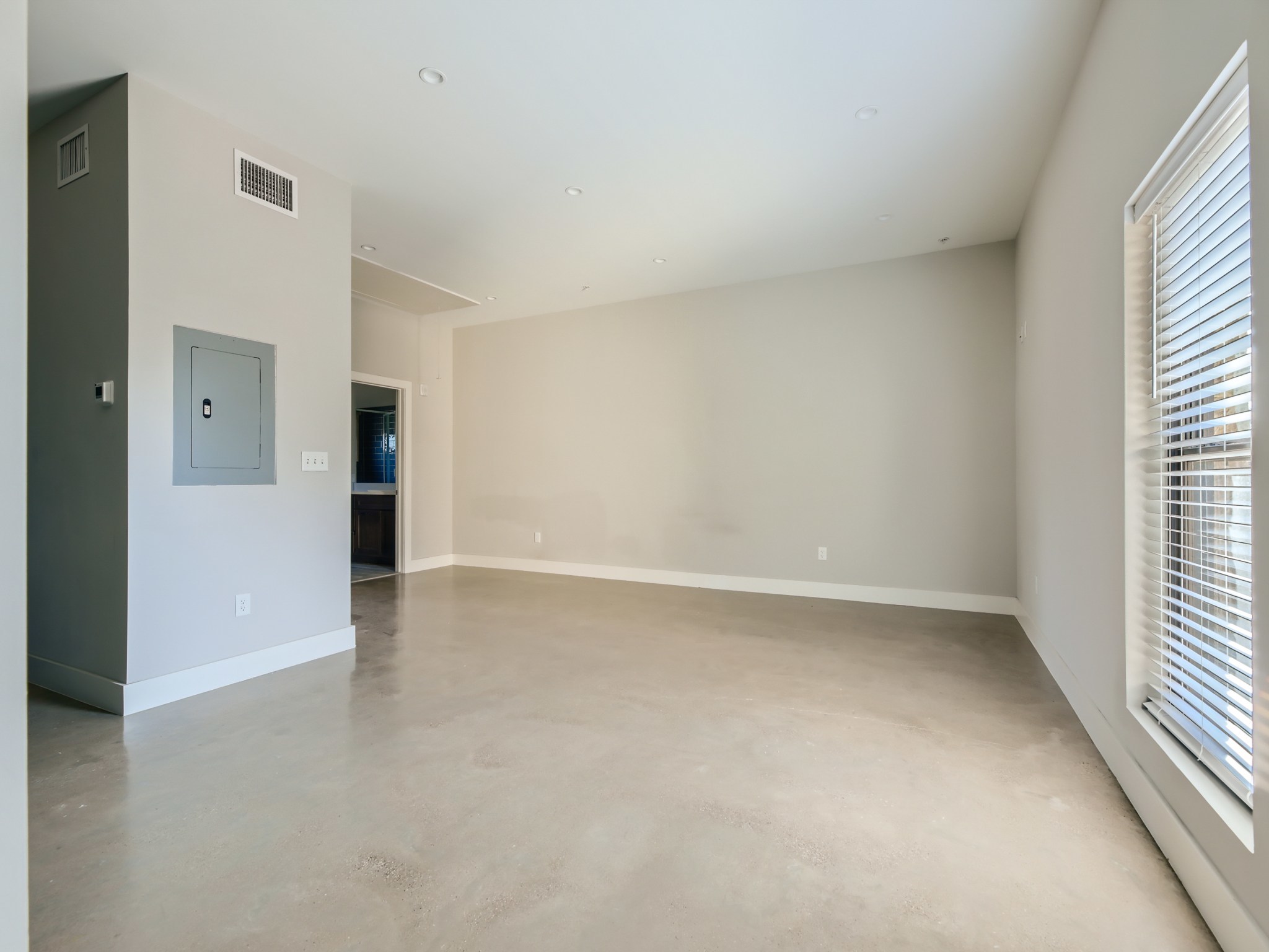 3523 Gonzalez Street, Unit 200 Austin, TX 78702 - Photo 2 of 10 Spacious room featuring light-toned concrete flooring, recessed lighting, a single window with horizontal blinds, and a neutral wall palette