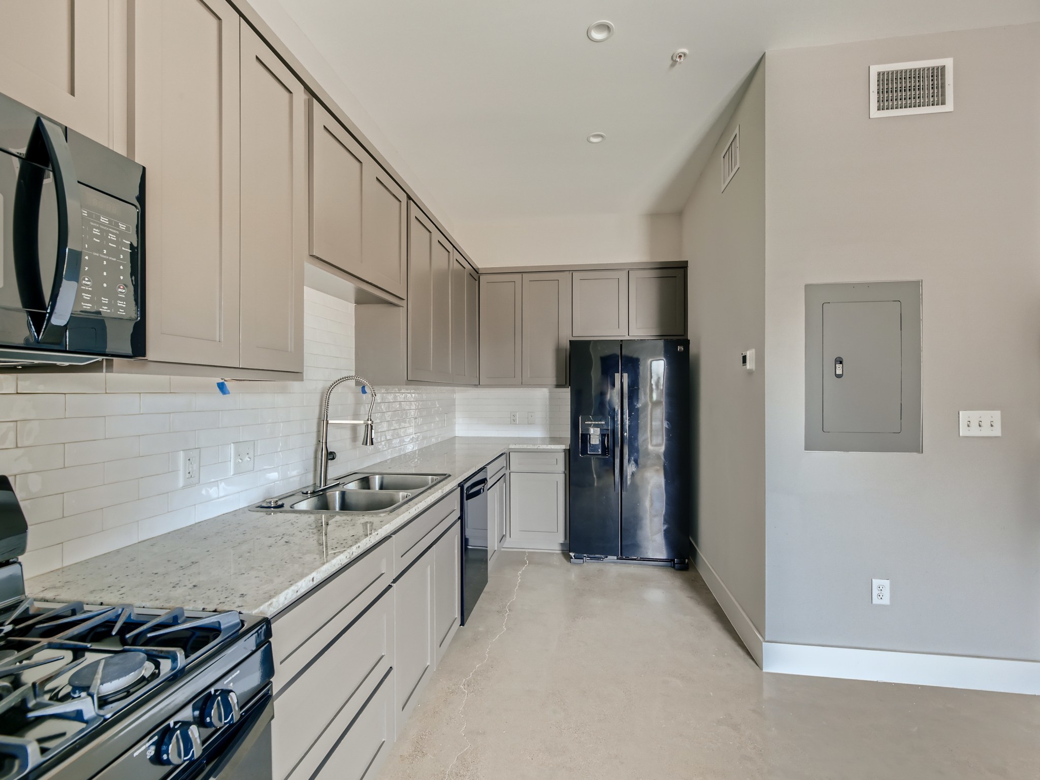 3523 Gonzalez Street, Unit 200 Austin, TX 78702 - Photo 5 of 10 Modern kitchen featuring light gray cabinetry, a dual basin stainless steel sink, a subway tile backsplash, and a built-in microwave