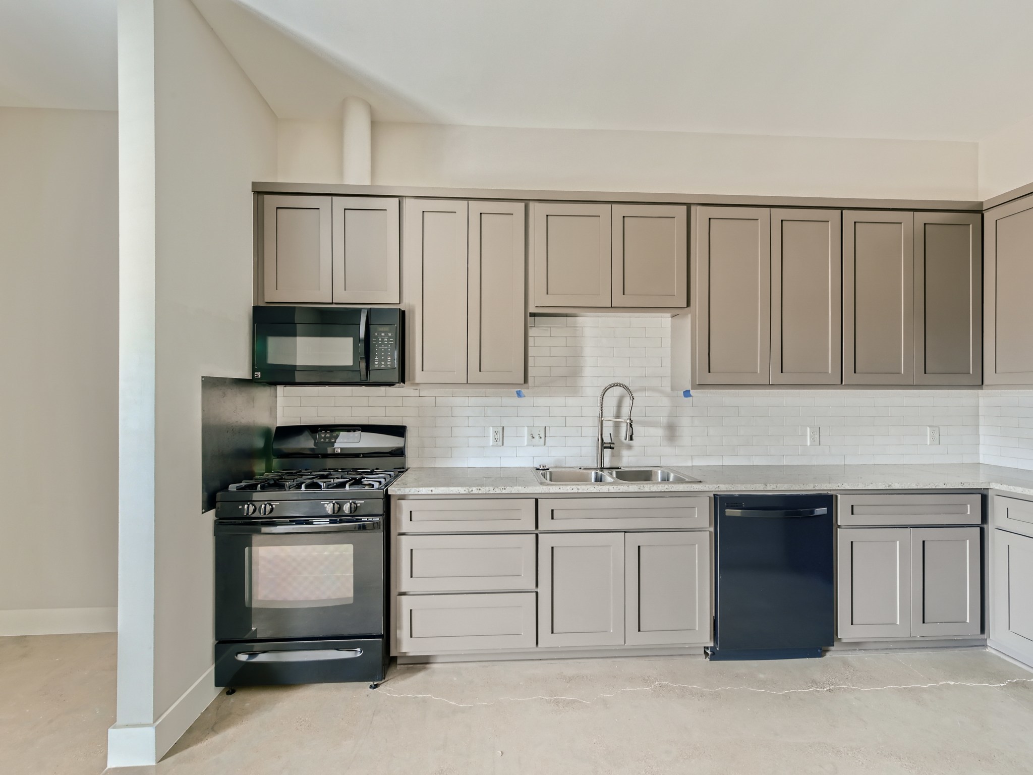 3523 Gonzalez Street, Unit 200 Austin, TX 78702 - Photo 6 of 10 Kitchen featuring neutral-toned cabinetry, subway tile backsplash, light-colored countertops, black appliances, and a stainless steel sink with a high-arc faucet