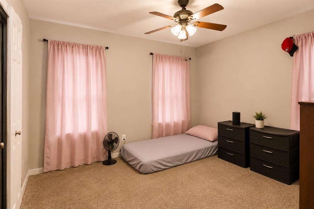 10505 Ferguson Road Dallas, TX 75228 - Photo 13 of 14 Carpeted interior room featuring a ceiling fan with light fixture, two windows, and light neutral wall paint