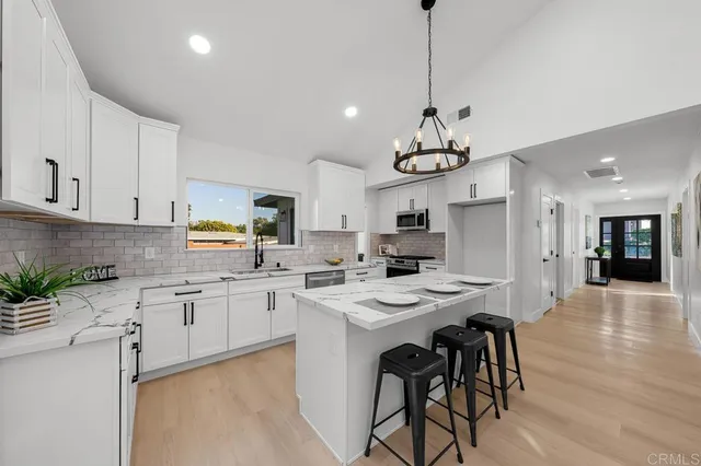 a kitchen with stainless steel appliances kitchen island granite countertop a sink a stove a dining table and chairs