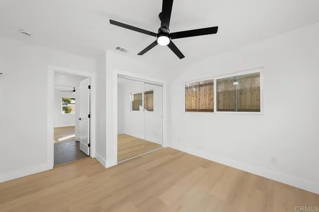 a view of a hallway with wooden floor and a ceiling fan