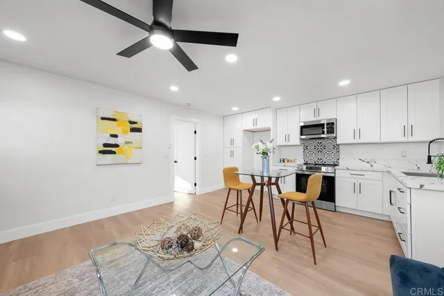 a kitchen with stainless steel appliances kitchen island granite countertop a dining table chairs refrigerator and sink