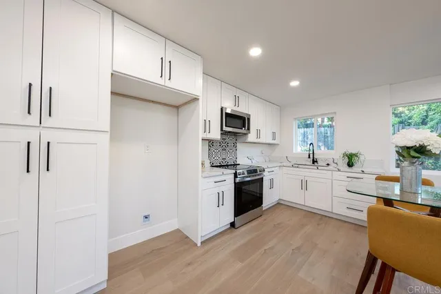 a large kitchen with cabinets wooden floor and stainless steel appliances