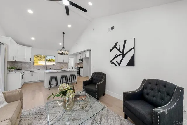 a living room with furniture kitchen view and a wooden floor