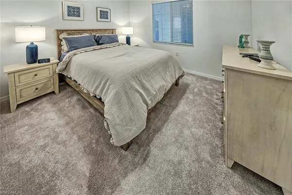 a spacious bedroom with a bed and a lamp on dresser