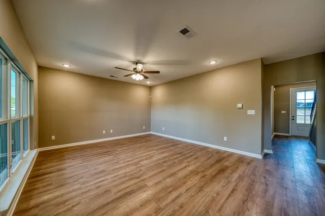 a view of an empty room with wooden floor and a chandelier