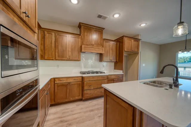 a kitchen with stainless steel appliances granite countertop a sink a stove and a refrigerator