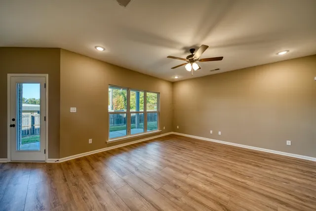 an empty room with wooden floor and a ceiling fan