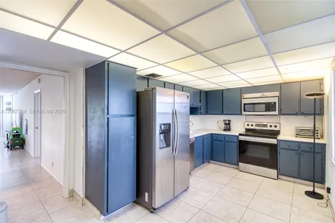 a large kitchen with stainless steel appliances granite countertop a refrigerator and a stove top oven