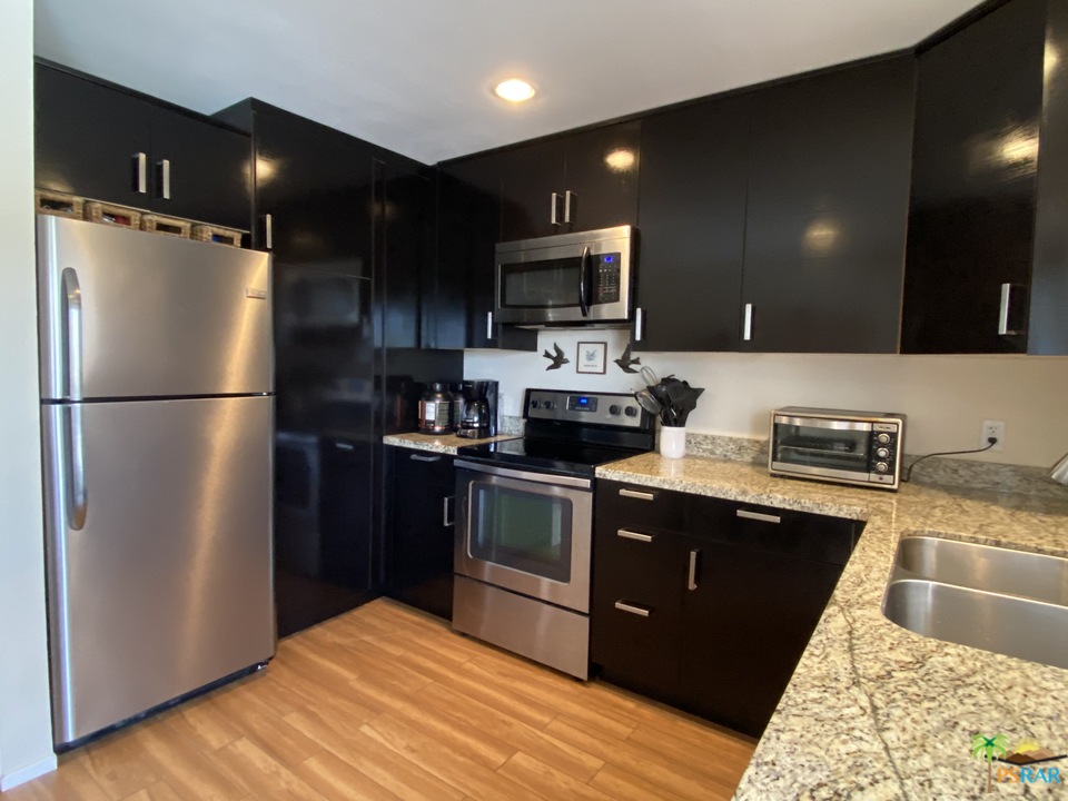 1268 Ramon Road, Unit 22 Palm Springs, CA 92264 - Photo 4 of 21 a kitchen with stainless steel appliances granite countertop a refrigerator a sink a stove a microwave and cabinets