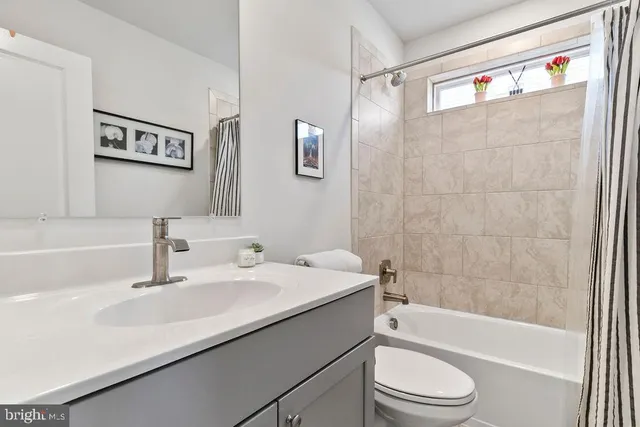 a bathroom with a sink a toilet a mirror a vanity a bathtub and shower