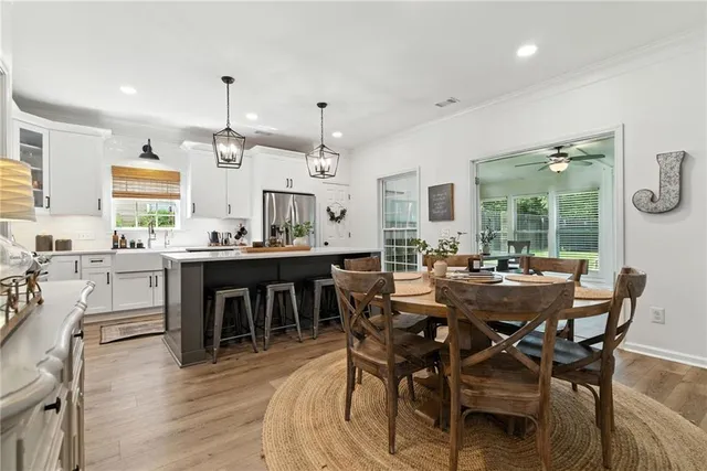 a view of a dining room and livingroom with furniture wooden floor a rug a painting and a chandelier