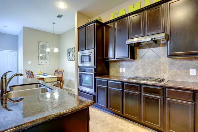 a kitchen with kitchen island granite countertop a sink and refrigerator