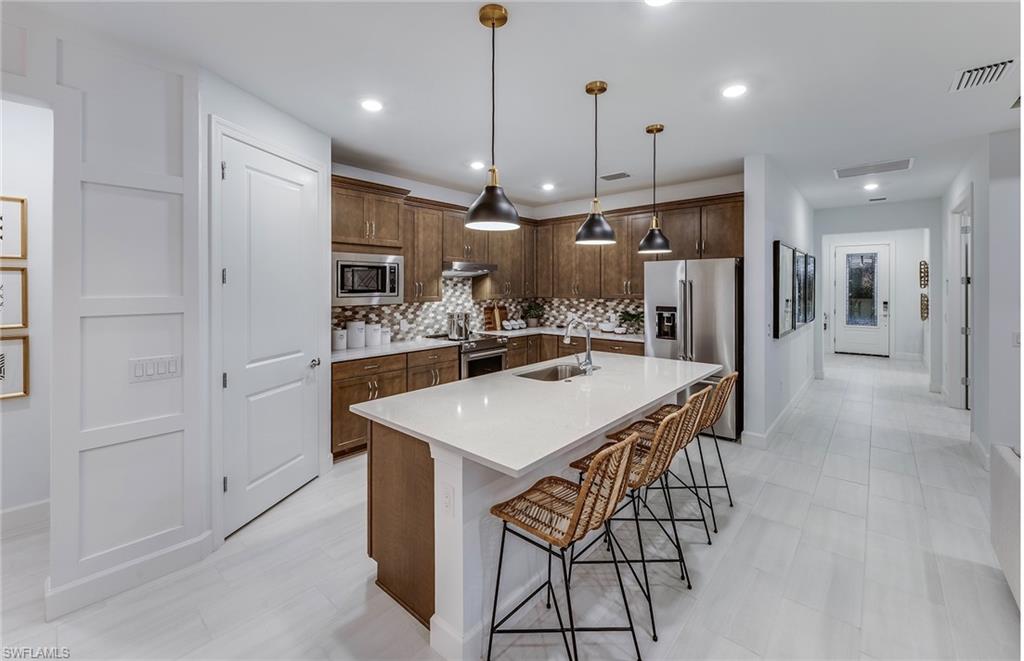 5637 Celebration Drive Immokalee, FL 34142 - Photo 8 of 35 a kitchen with stainless steel appliances a refrigerator a sink a stove a kitchen island with a refrigerator and cabinets