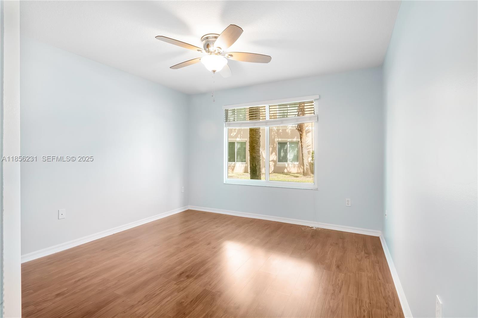 1308 Villa Circle, Unit 1308 Boynton Beach, FL 33435 - Photo 18 of 35 an empty room with wooden floor chandelier fan and windows