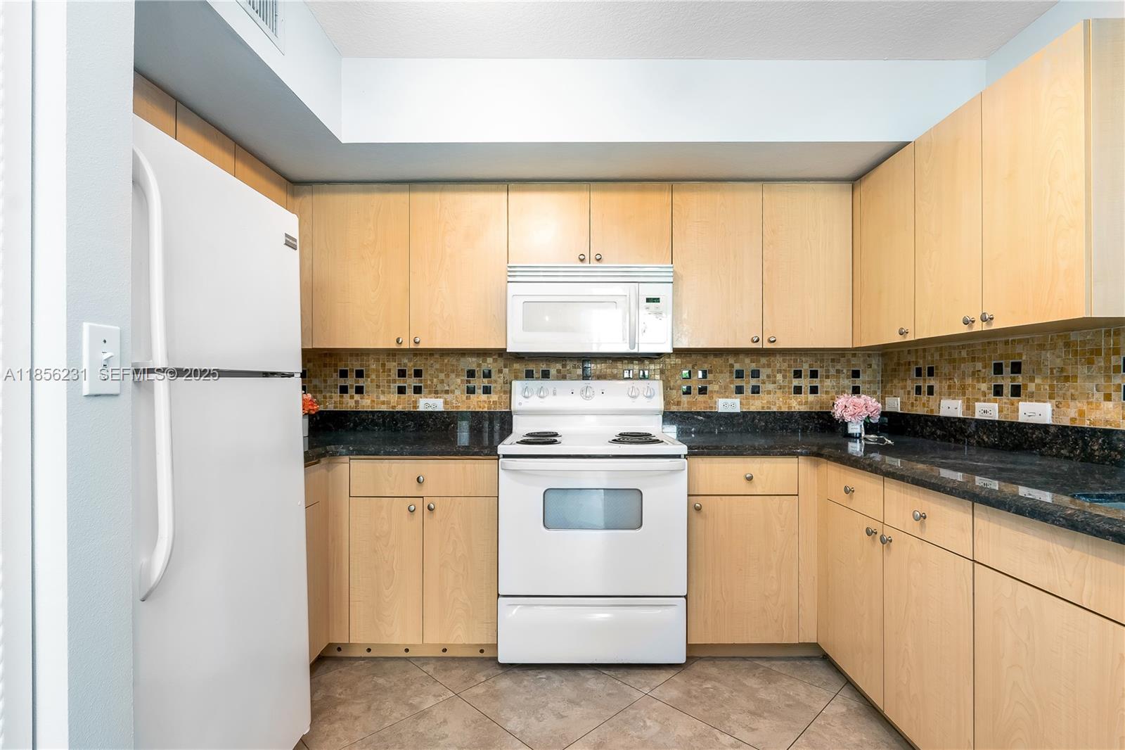 1308 Villa Circle, Unit 1308 Boynton Beach, FL 33435 - Photo 7 of 35 a kitchen with a stove a sink and white cabinets