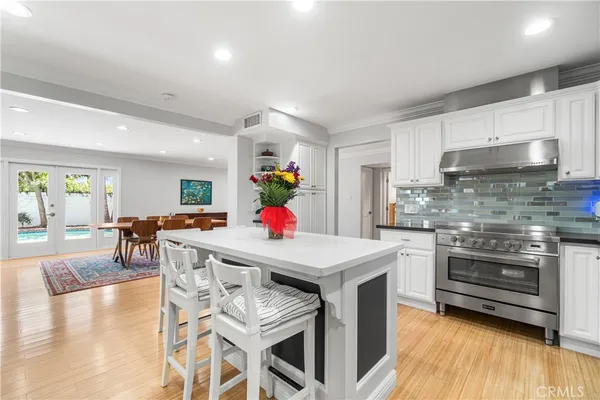 a kitchen with a stove a refrigerator and a dining table with wooden floor