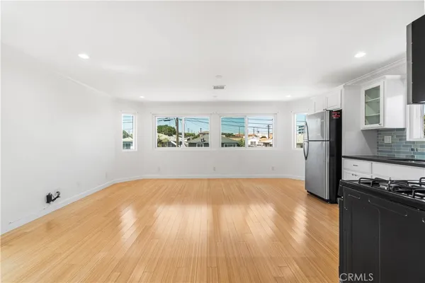 a view of a kitchen with kitchen island wooden floor and stainless steel appliances