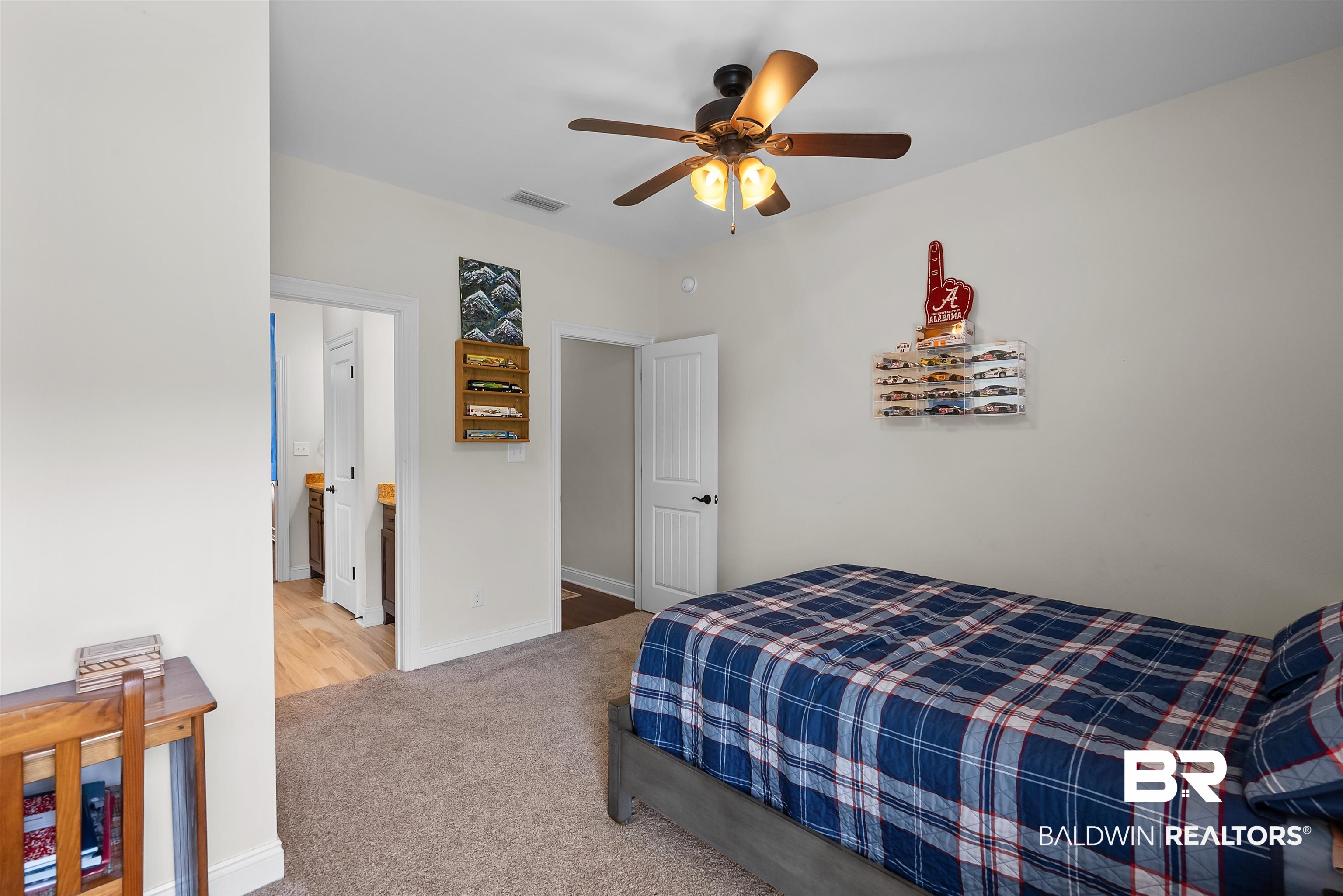 12070 Comalander Road Fairhope, AL 36532 - Photo 34 of 50 Carpeted room featuring a ceiling fan with integrated lighting, a white painted door, and an open doorway revealing wood-finish flooring