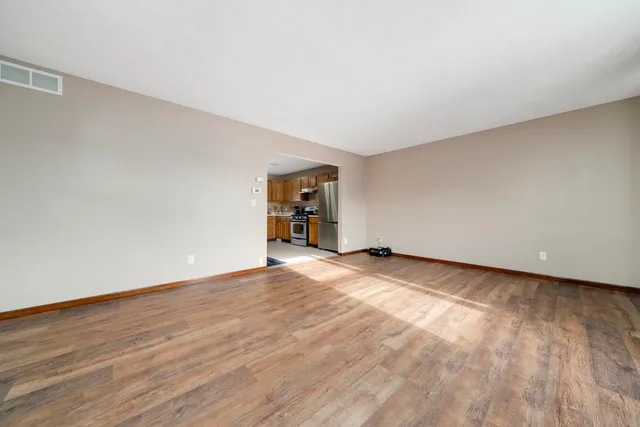 a view of an empty room with a window and wooden floor