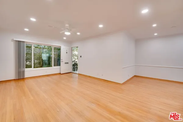 a view of an empty room with wooden floor and a window