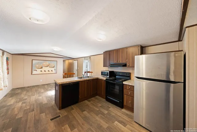 a kitchen with granite countertop a refrigerator a stove top oven and a refrigerator