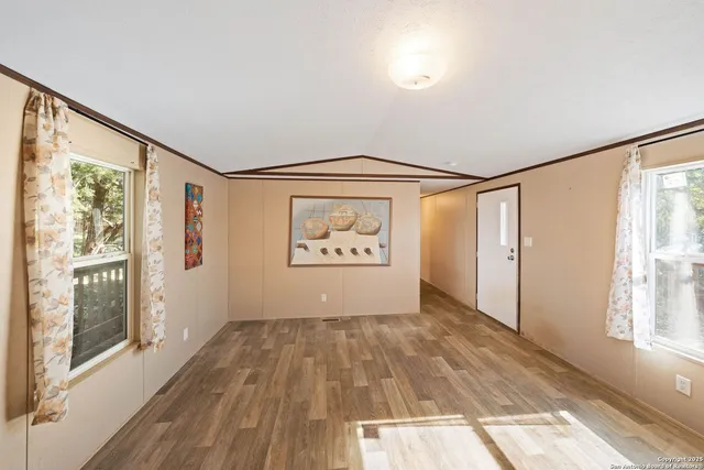 a view of an empty room with a window and wooden floor