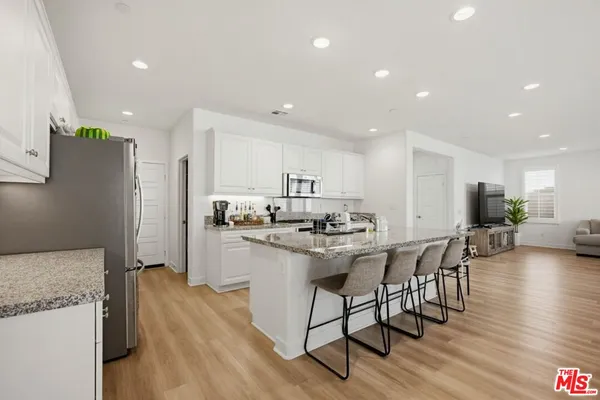 a kitchen with stainless steel appliances kitchen island granite countertop a table chairs stove and white cabinets