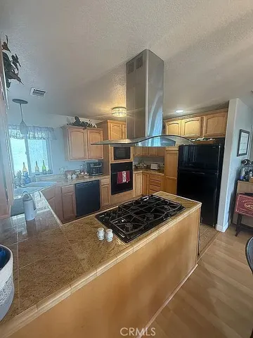 a kitchen with kitchen island a stove a refrigerator a sink a dining table and chairs with wooden floor