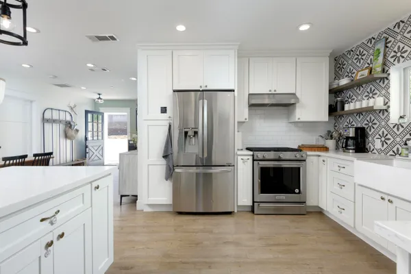 a kitchen with stainless steel appliances granite countertop a refrigerator a stove a sink and white cabinets