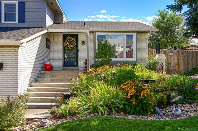 a view of a house with potted plants and a table and chairs